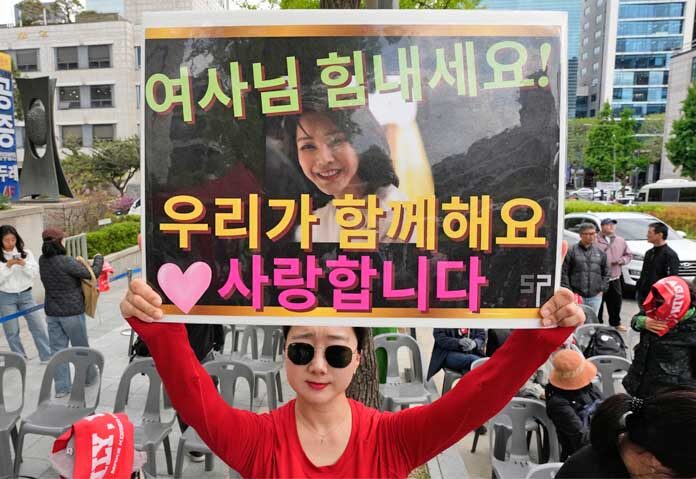 ผู้สนับสนุนอดีตประธานาธิบดีเกาหลีใต้ ยุน ซุก ยอล ถือป้ายที่มีรูปภาพของภรรยาของเขา คิม กอน ฮี ระหว่างการชุมนุมนอกศาลสูงกรุงโซล ประเทศเกาหลีใต้ เมื่อวันอังคารที่ 28 เมษายน 2569 ข้อความบนป้ายเขียนว่า "เข้มแข็งไว้นะ คุณผู้หญิง!" และ "เรารักคุณ"