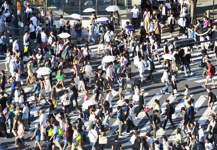 ญี่ปุ่นทุบสถิติร้อนระดับ - ผู้คนกางร่มเพื่อบังแดดขณะเดินข้ามทางแยกในวันจันทร์ที่ 17 กรกฎาคม 2566 ในกรุงโตเกียว