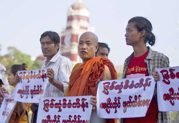 กลุ่มนักกิจกรรมและพระภิกษุสงฆ์ถือป้ายประท้วงโครงการเขื่อนมิตโซนบนแม่น้ำอิรวดีในรัฐคะฉิ่น เมื่อวันจันทร์ที่ 25 มีนาคม 2562 หน้าศาลาว่าการเมืองย่างกุ้ง ประเทศเมียนมาร์ กลุ่มนักกิจกรรมเรียกร้องให้ยกเลิกโครงการเขื่อนไฟฟ้าพลังน้ำที่ได้รับการสนับสนุนจากจีนอย่างสิ้นเชิง เนื่องจากความกังวลด้านสิ่งแวดล้อม ป้ายดังกล่าวมีข้อความว่า "หยุดโครงการเขื่อนมิตโซนอย่างสิ้นเชิง"