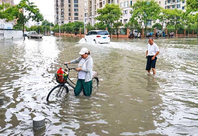 เฝ้าระวังขั้นสูง - ภาพถ่ายนี้เผยแพร่โดยสำนักข่าวซินหัว แสดงให้เห็นชาวบ้านพยายามสัญจรผ่านถนนที่ถูกน้ำท่วมหลังพายุไต้ฝุ่นบาบีพัดถล่มในเมืองเย่ว์ชิง มณฑลเจ้อเจียง ทางตะวันออกของจีน เมื่อวันที่ 12 กรกฎาคม 2569