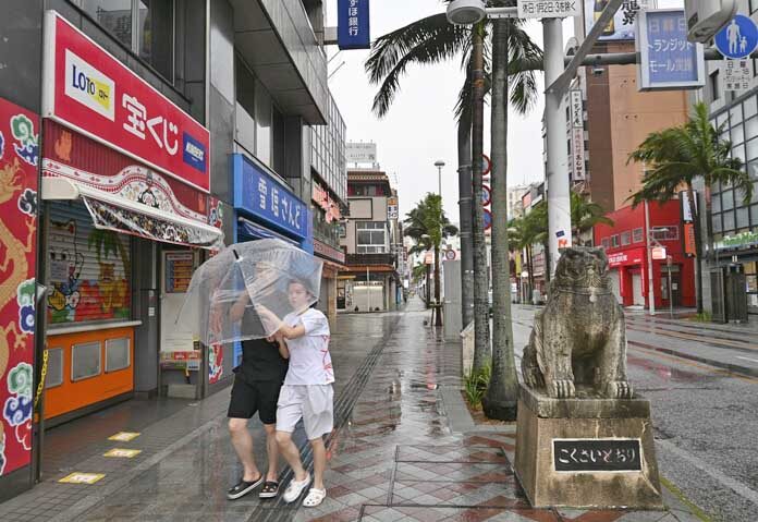 ผู้คนเดินท่ามกลางสายฝนขณะที่พายุไต้ฝุ่นดอลฟินกำลังเข้าใกล้เมืองนาฮา ประเทศญี่ปุ่น วันศุกร์ที่ 7 สิงหาคม 2569
