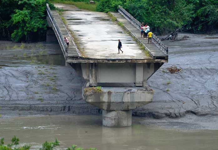 ประชาชนยืนอยู่บนซากสะพานที่เคยทอดข้ามแม่น้ำตรีศุลี ซึ่งถูกพัดพังไปในเหตุการณ์น้ำท่วมฉับพลัน ในเขตธาดิง ประเทศเนปาล เมื่อวันอาทิตย์ที่ 30 สิงหาคม 2569