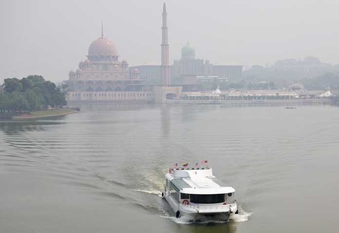 เรือนำเที่ยวลำหนึ่งแล่นผ่านมัสยิดปุตราและสำนักนายกรัฐมนตรีมาเลเซีย ท่ามกลางหมอกควันที่เกิดจากไฟป่าในภูมิภาค ที่เมืองปุตราจายา ประเทศมาเลเซีย เมื่อวันที่ 7 ตุลาคม 2026