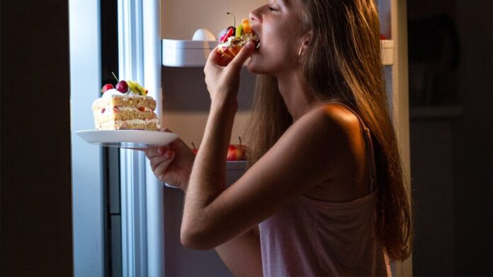 หญิงสาวกำลังหยิบของกินจากตู้เย็นมารับประทาน