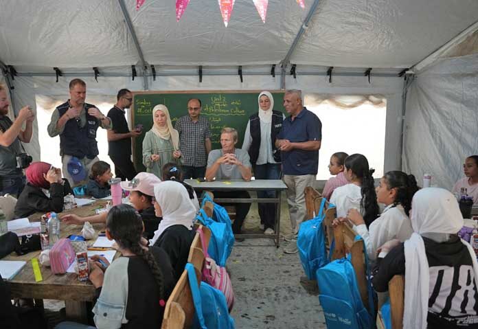 คาร์ล สเกา (Carl Skau) ผู้อำนวยการบริหารโครงการอาหารโลก (World Food Programme) (กลาง) เยี่ยมชมเต็นท์ที่ถูกดัดแปลงเป็นห้องเรียนในเมืองเดียร์อัลบาลาห์ (Deir al-Balah) บริเวณตอนกลางของฉนวนกาซา เมื่อวันอาทิตย์ที่ 18 ตุลาคม 2026